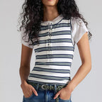 Woman wearing a striped shirt and jeans against a plain background