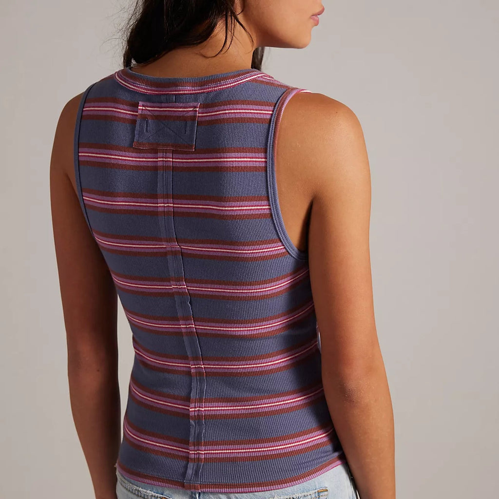 Woman wearing a striped tank top and jeans against a plain background