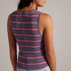 Woman wearing a striped tank top and jeans against a plain background