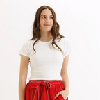 Woman wearing cream short-sleeve crewneck top with red pants and white stitching details