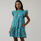 Woman wearing turquoise floral smocked mini dress with ruffled cap sleeves and tiered skirt
