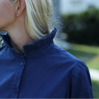 Person wearing a blue shirt with a blurred outdoor background