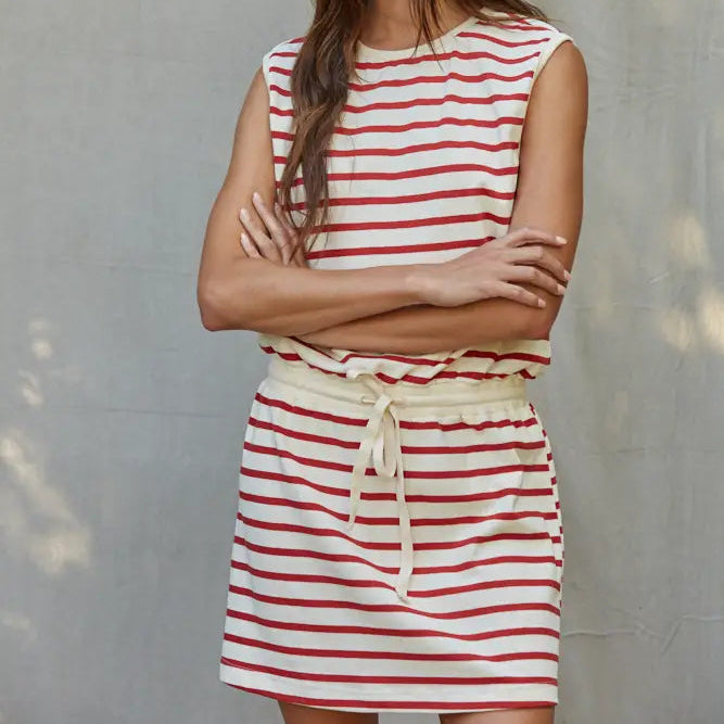 Woman wearing a red and white striped dress against a gray wall.