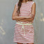 Woman wearing a red and white striped dress against a gray wall.