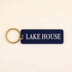 Navy blue rectangle keychain with gold ring and white LAKE HOUSE text on cream background