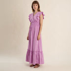 Woman wearing a purple dress with ruffled sleeves on a beige background