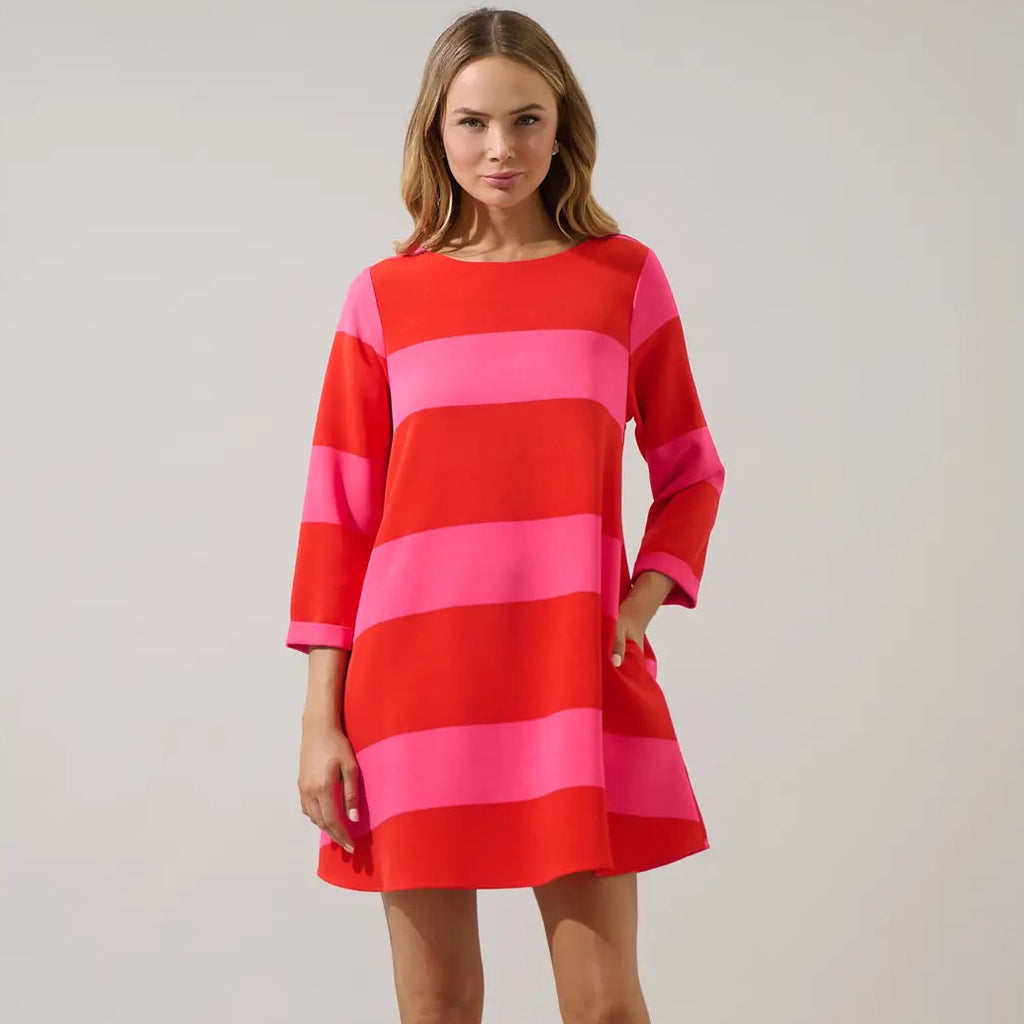 Woman wearing red and pink striped long-sleeve shift dress with horizontal color-block stripes and knee-length hemline