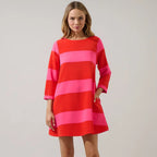 Woman wearing red and pink striped long-sleeve shift dress with horizontal color-block stripes and knee-length hemline