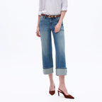 Woman wearing light purple button-up shirt, brown belt, and low rise straight leg crop jeans with rolled cuffs and burgundy …