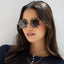 Woman wearing Luna tortoiseshell cat-eye sunglasses with gold-tone metal frames and dark lenses, styled with layered gold ne…
