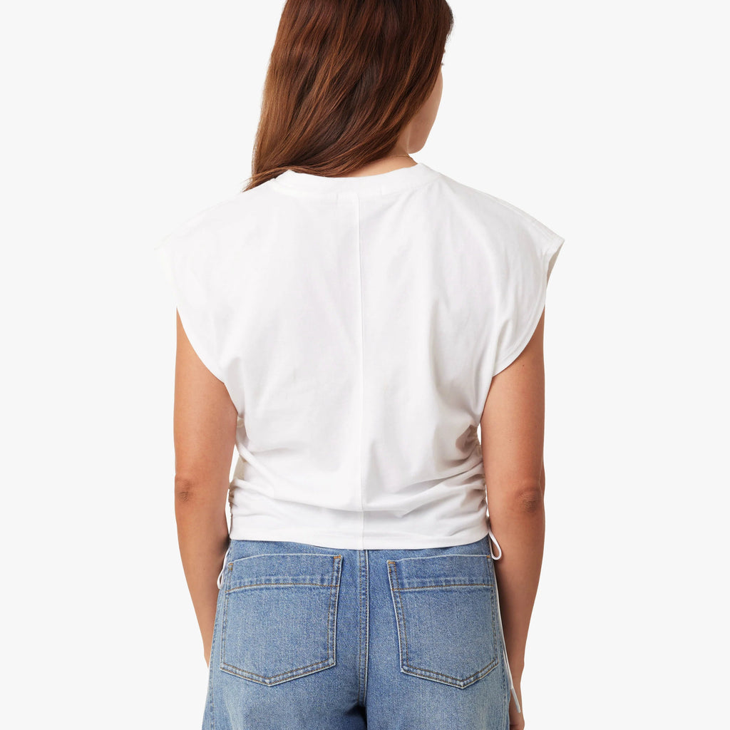 Person wearing a white sleeveless top and blue jeans on a white background