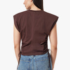 Person wearing a brown sleeveless top and blue jeans on a white background