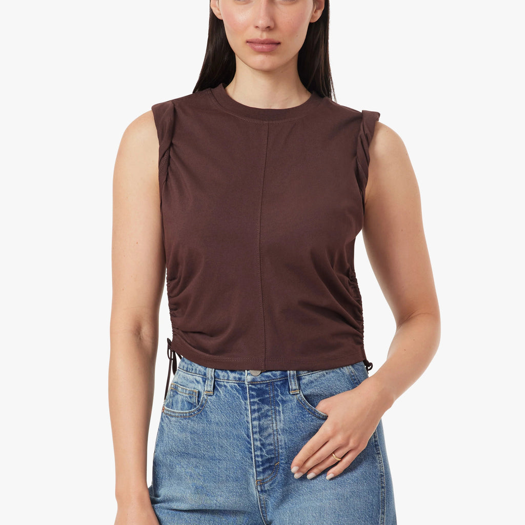 Woman wearing a brown sleeveless top and blue jeans on a white background