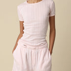 Woman wearing a light pink t-shirt and shorts on a beige background