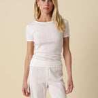 Woman wearing a white outfit against a beige background