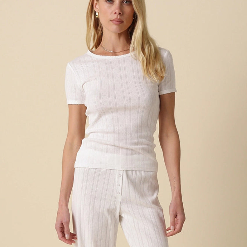 Woman wearing a white outfit against a beige background