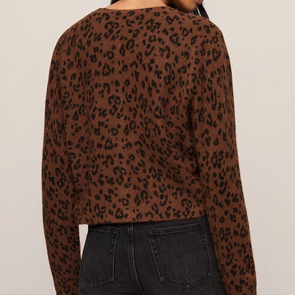 Person wearing a brown leopard print top and black jeans on a beige background