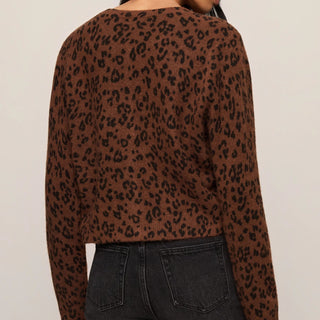 Person wearing a brown leopard print top and black jeans on a beige background