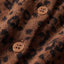 Close-up of a brown textured fabric with a black leopard print pattern and two round buttons.
