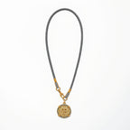 Necklace with a gold pendant on a gray cord against a white background