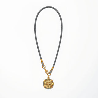 Necklace with a gold pendant on a gray cord against a white background