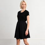 Woman wearing black Modern Classic Dress with short sleeves and knee-length skirt, standing against white background