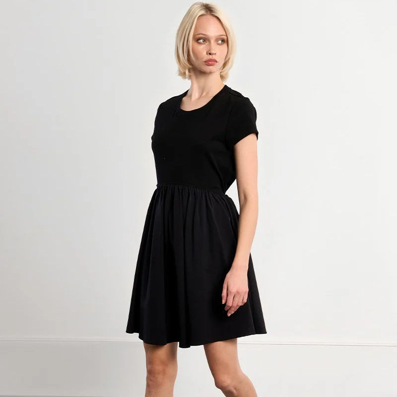 Woman wearing black Modern Classic Dress with short sleeves and knee-length skirt, standing against white background