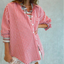 Woman wearing red and white gingham oversized button-down shirt with rolled sleeves over white distressed shorts