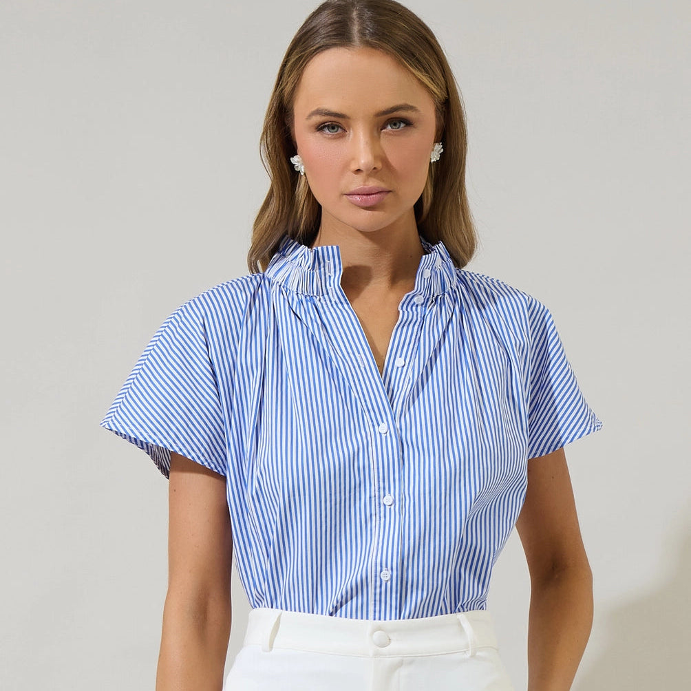 Woman wearing blue and white striped short-sleeve button-up shirt with mock neck collar and white pearl stud earrings