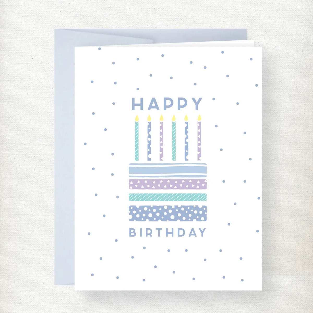 Happy Birthday greeting card featuring a colorful patterned cake with six lit candles and blue polka dot background