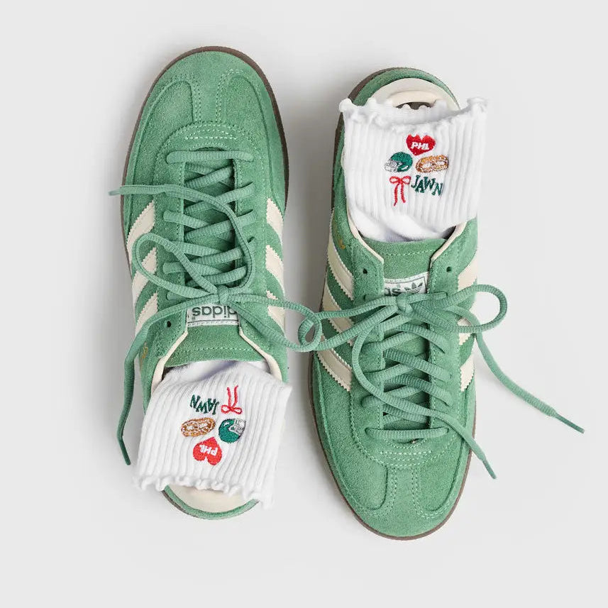 A pair of mint green low-top sneakers with white socks peeking out from the toes, photographed from above on a light gray background.