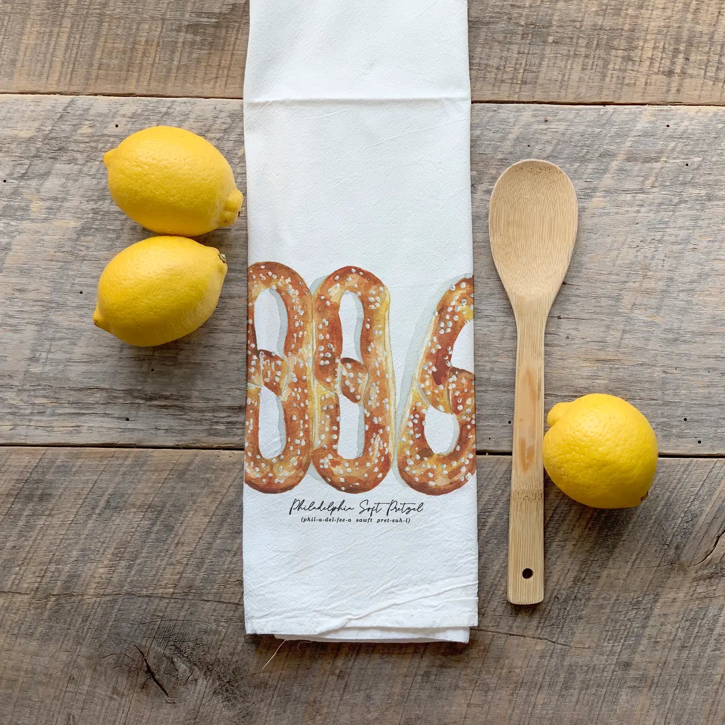 Philly Pretzel flour sack towel displayed with fresh lemons and a wooden spoon on wooden surface Main image