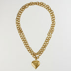 A gold-toned double-strand chain necklace with a polished heart-shaped pendant, displayed against a solid white background.