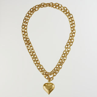 A gold-toned double-strand chain necklace with a polished heart-shaped pendant, displayed against a solid white background.
