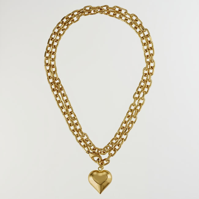 A gold-toned double-strand chain necklace with a polished heart-shaped pendant, displayed against a solid white background. Main image
