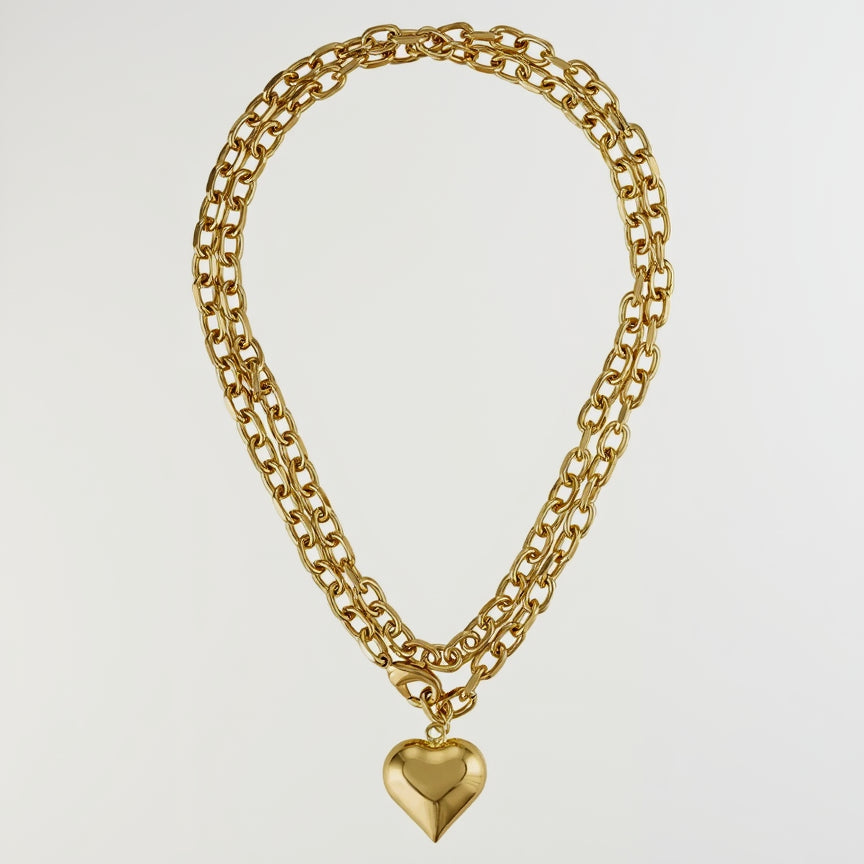 A gold-toned double-strand chain necklace with a polished heart-shaped pendant, displayed against a solid white background. Main image