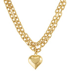 A gold-toned double-strand chain necklace featuring a polished heart-shaped pendant, shown against a plain white background.