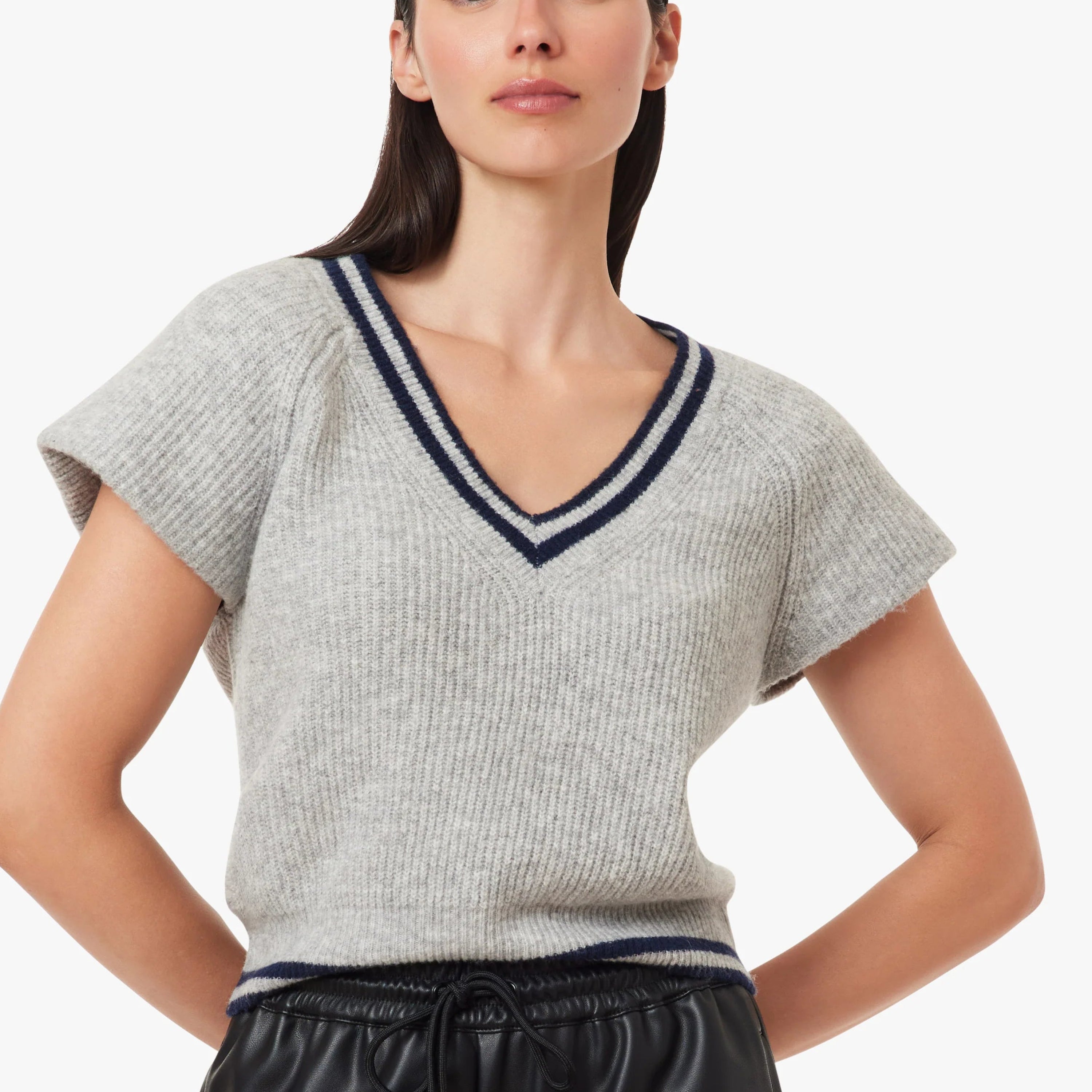 A woman modeling a light gray ribbed knit V-neck sweater with navy blue trim, paired with black pants, against a plain light gray background. Main image