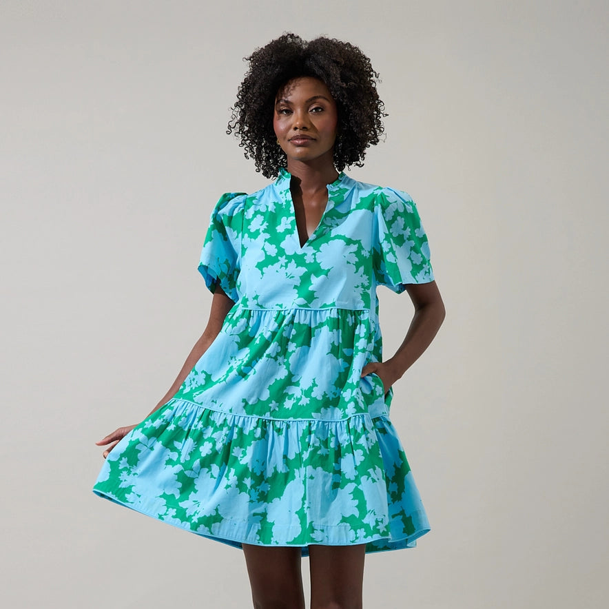 Woman wearing Riona Floral Candace Tiered Mini dress in turquoise and green floral print with short sleeves and tiered skirt Main image