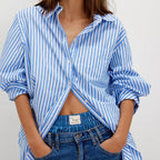 Woman wearing Free People Sabine tailored striped shirt in blue and white with rolled sleeves, styled with dark denim jeans