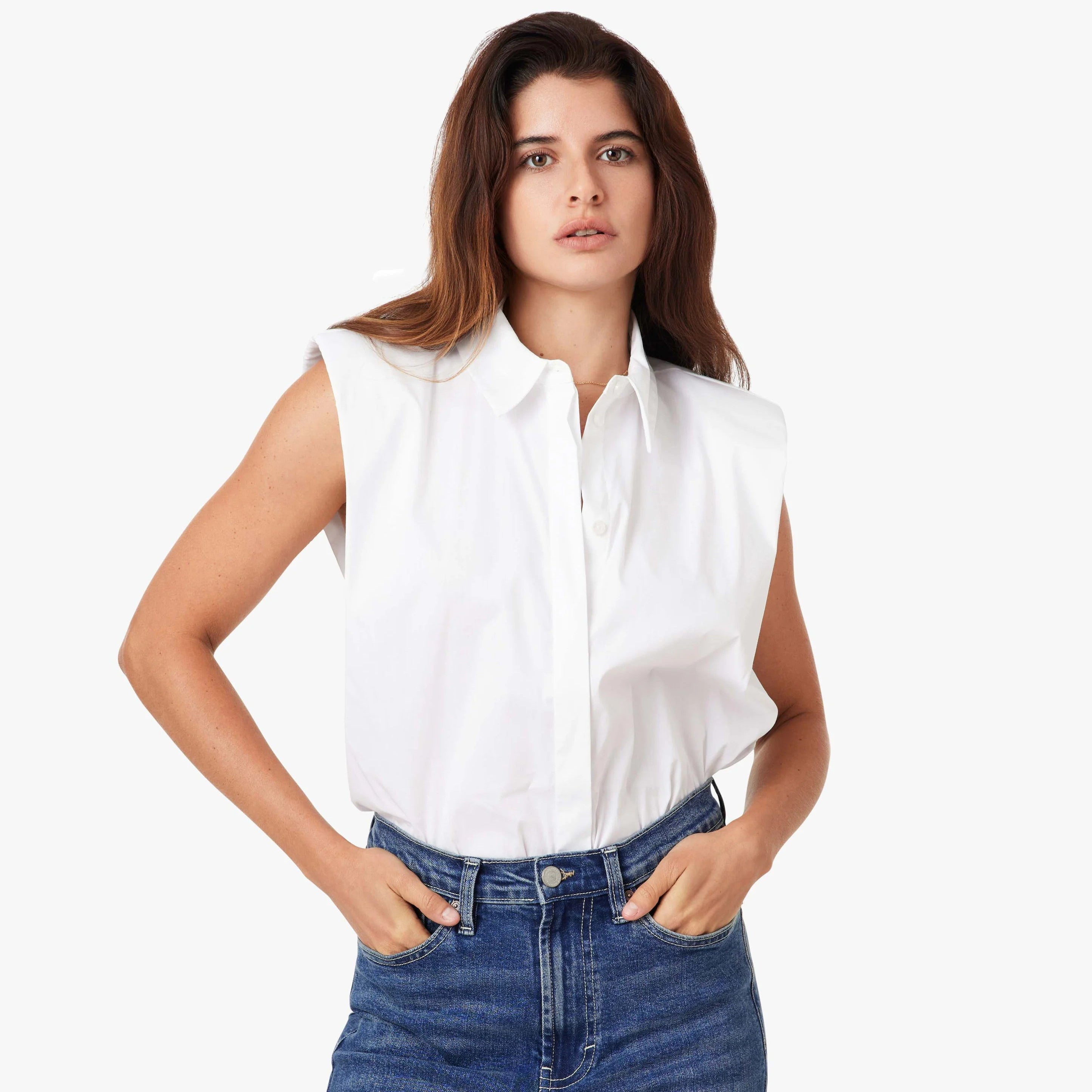 Woman wearing white sleeveless shoulder pad shirt with collar, paired with blue denim jeans