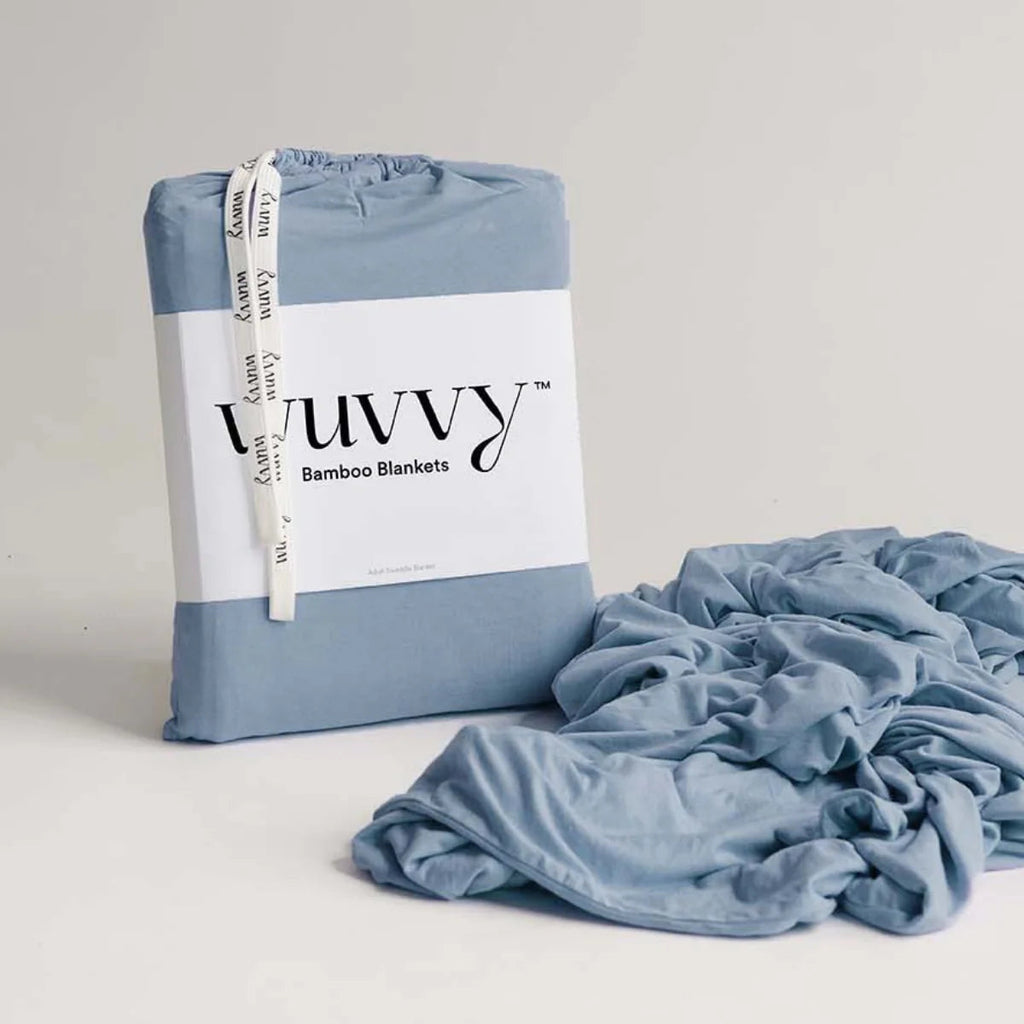 Wuvvy bamboo blanket packaged in blue and white branded wrapping with ribbon, displayed next to folded soft blue fabric