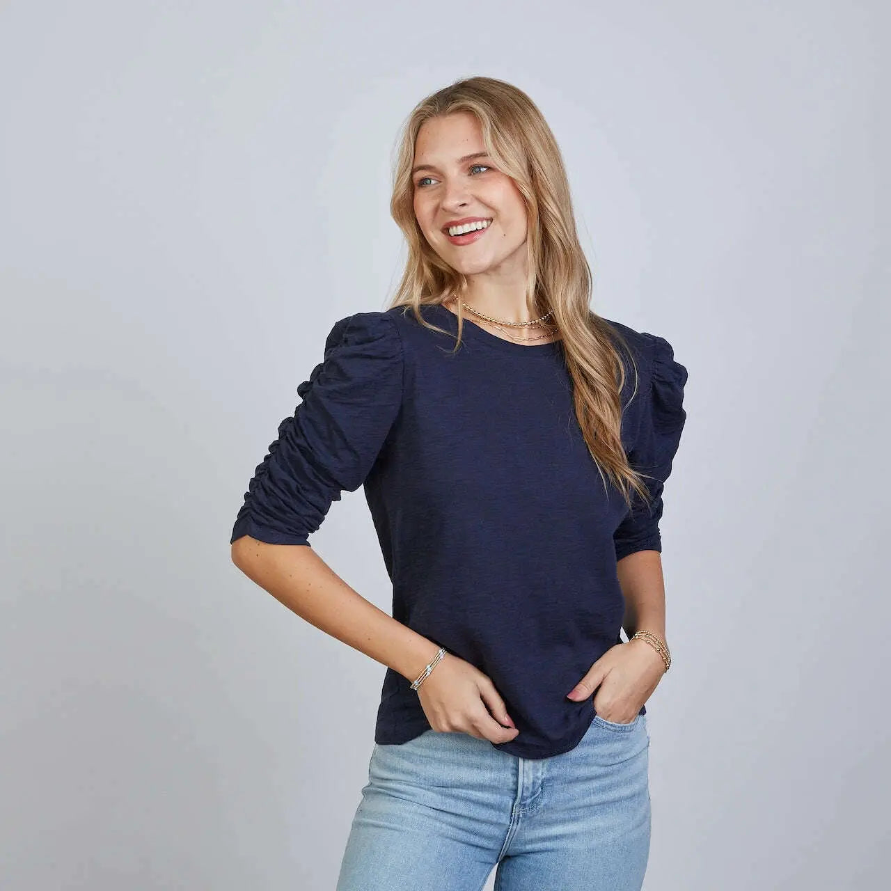 Woman wearing navy Sophie Ruched Elbow Length Tee with puffed sleeves, paired with light blue jeans