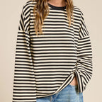 Woman wearing black and cream striped oversized long sleeve terry top with ruched side detail, paired with light blue jeans