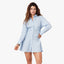 Woman wearing light blue striped mini shirt dress with long sleeves and collar, paired with hand on hip pose against white b…