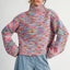 Woman wearing a colorful knitted sweater and blue jeans on a white background