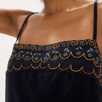 Woman wearing a black dress with intricate gold beading
