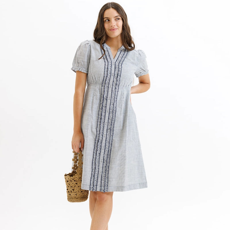 Woman wearing light gray Tuxedo Pinstripe Ruffle Dress with short puffed sleeves, holding a woven straw handbag Main image