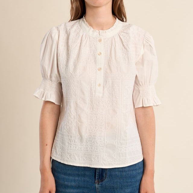 Woman wearing a white blouse with short sleeves and blue jeans on a beige background